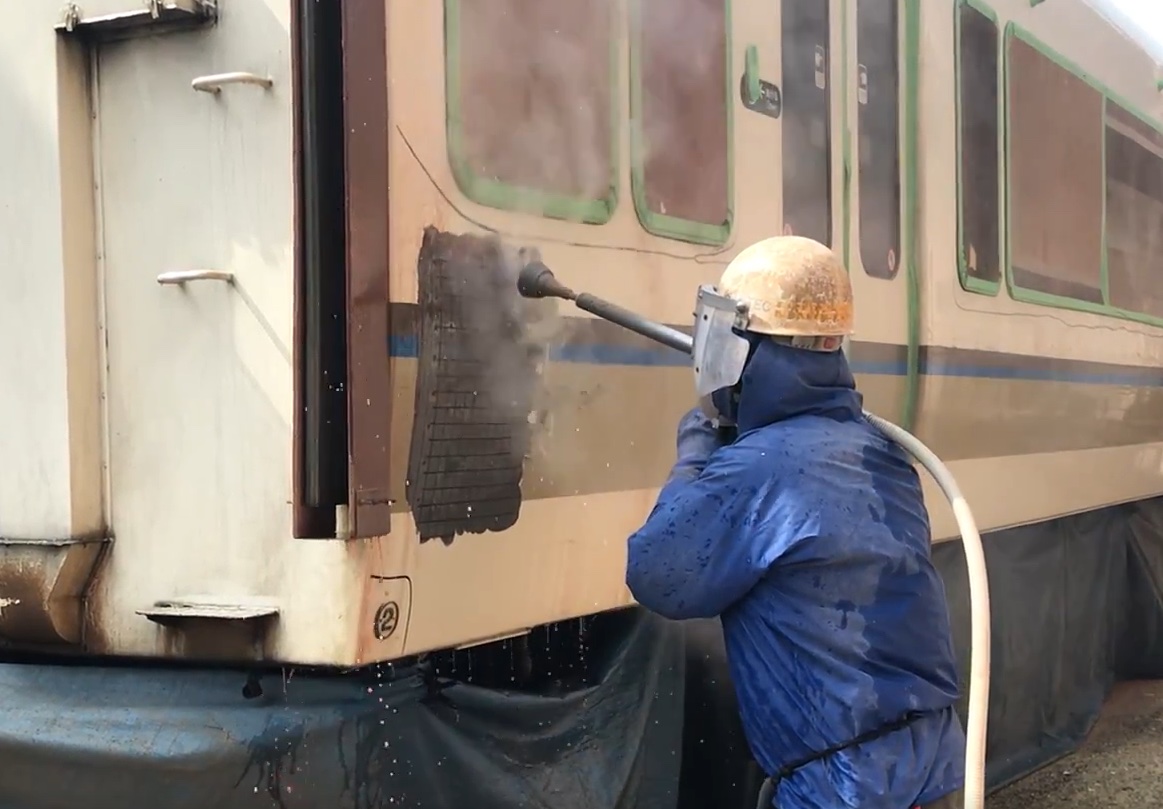 鉄道車両の外板塗膜を超高圧ウォータージェットで除去している様子
