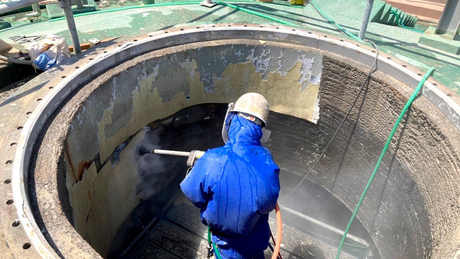 下水処理場の円形水槽内で、超高圧ウォータージェットにより劣化した防食塗膜を除去している様子